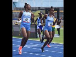Tina Clayton (left) looks over at her twin sister Tia (right) as they cross the finish line in the  100 metres ahead of Thennel Williams (right) and Kacy-Ann Johnson (second left) during the JAAA All Comers meet at the National Stadium last Saturday. Tina won the race in 11.71 seconds.
