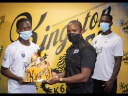 Cavalier’s Dwayne Atkinson (left) accepts a Kingston 62 gift package from Kamal Powell,  Regional Marketing Manager, J. Wray and Nephew Limited, at the Jamaica Football Federation head office in New Kingston yesterday. Looking on at right is Cavalier’s Kamoy Simpson.