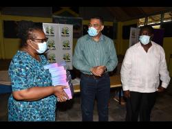 Prime Minister Andrew Holness (centre) talks with Uvelyn Barrett-Rose (left), principal of Labyrinth Primary School, shortly after he presented 10 tablet computers to the school during a handover ceremony. Looking on is Robert Montague, member of parliament for Western St Mary, in which the school is located.