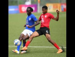 Mount Pleasant’s Kesslon  Hall (left)  under pressure from Luca Kung of Arnett Gardens  during yesterday’s Jamaica Premier League match at the UWI/Captain Horace Burrell Centre of Excellence.