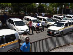 Taxis await passengers in Half-Way Tree on Monday, when the new fares went into effect.