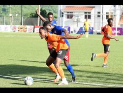 Earon Elliott  (front) of Tivoli Gardens shielding the ball from Dunbeholden’s Romario McPherson during their  Jamaica Premier League match at the UWI/Captain Horace Burrell Centre of Excellence on Monday. The match ended 1-1.