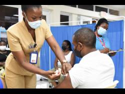Public health nurse Natasha Bently vaccinates Winston Grant  during a vaccination drive at the University Hospital of the West Indies last Thursday.