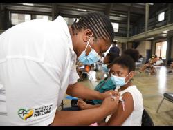 Public health nurse Pauline Simpson administers a dose of Pfizer to Lee-Anne Oakley during a vaccination blitz held at Jamaica College on August 23. 