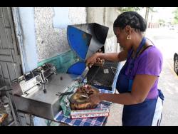 Clevette Folkes-Straw prepares some of her jerk chicken at her little shop on North Street, downtown Kingston.