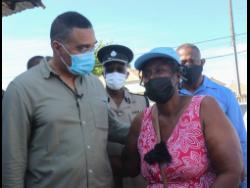 Prime Minister Andrew Holness consoles Mable Forbes whose son, Duvaughn Brown, was shot and killed in Naggo District, Westmoreland on Wednesday night.
