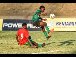 Jayden Foster (right) of Calabar High hurdles a tackle by Zidane Clarke of Kingston High  during yesterday’s Manning Cup match at the Stadium East field. Kingston High won 1-0. 