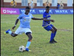 Credit: Kavarly Arnold Edwin Allen High’s Ackeem Mullings (left) attempts a long pass after getting away from Christiana High’s Omari Brown during their ISSA/Digicel daCosta Cup quarter-final match at Manchester High yesterday. Edwin Allen won 4-0.