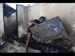 Shantae Blake shows her 55” television that was destroyed by a fire at Young Street in Spanish Town, St Catherine, early yesterday.