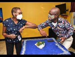 Garfield Angus (right) is greeted by Beverley Francis, manager for the editorial and photography department at the Jamaica Information Service,  during a celebratory function to mark Angus’ 30th anniversary in journalism.