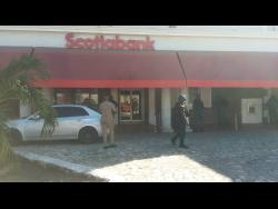 Police and Jamaica Defence Force personnel cordon the outside of the Scotiabank outlet in Sam Sharpe Square, Montego Bay, where a armed robber was shot and killed by security guards while he attempted to rob the establishment yesterday morning. 