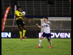 Jamaica’s Javain Brown (left) brings the ball down while being tracked by USA’s Christian Pulisic during a World Cup qualifying match at the National Stadium on Tuesday, November 16, 2021.