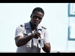 Constable Joel Robinson preaches in Dunkirk in Kingston after gunmen invaded the community last Friday, killing two persons.