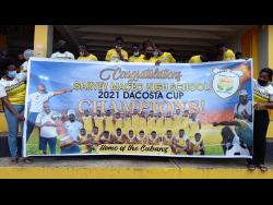 Garvey Maceo High School’s ISSA/WATA daCosta Cup winning team displays a banner commemorating their success during their celebration on school grounds in Gimme-Me-Bit, Clarendon, yesterday.