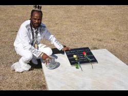 L.A. Lewis, with his crystal ball, at the grave of former prime minister Edward Seaga at National Heroes Park in Kingston yesterday.