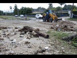 A National Works Agency-contracted operator clears a roadway in Runaway Bay, St Ann, after floodwaters receded on Tuesday. 