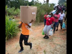 Persons carry goods down the dirt track which leads to the Tuckers’ home.
