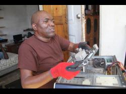Dean Anthony Whyte works on a PC at his home in Clarendon.