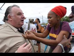 Jamaican reggae artiste Queen Ifrica (right) animatedly makes a point to Andrew Lumsden, a financial adviser, as they participate in an anti-royalist protest near the British High Commission in New Kingston on Tuesday. 