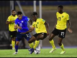 Jamaica's Damion Lowe (right) looks on while teammate Gregory Leigh (centre) is challenged by El Salvador's Bryan Tamacas during their Concacaf World Cup qualifying match at the National Stadium in Kingston on Thursday night.