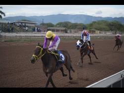 Crimson, ridden by Dane Nelson, wins the Lloyd Lindberg ‘Lindy’ Delapenha Memorial Trophy over a mile at Caymanas Park in St Catherine yesterday.