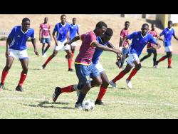 St Andrew Technical High School’s Omar Laing (centre), takes on Camperdown High players during a Manning Cup match last November.