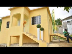 Courtney Williams makes a phone call while sitting on the steps of his new three-bedroom house at Schoolfield in Santa Cruz, St Elizabeth, recently. The house for the family of six was provided under the New Social Housing Programme.