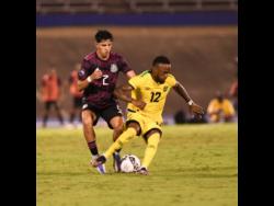 Jamaica’s Junior Flemmings (right) shielding the ball from Mexico’s Kevin Alvarez during last night’s Concacaf   Nations League football match at the National Stadium. The game ended in a 1-1 draw. 