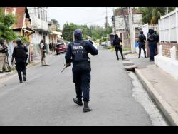 Members of the security forces maintain a presence along French Williams streets in Spanish Town yesterday, following attacks by gunmen.