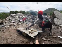 Orlando Joseph roasts fish and crackers on the spot where his bedroom used to be.