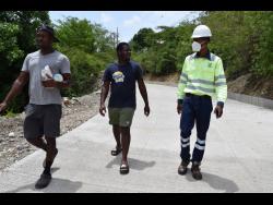 Caribbean Cement Company Limited’s social impact specialist, Jerome Cowans (right), engages in discussion with  Andral Doyley (centre) and Ian Barrett during a visit to Cambridge in Eleven Miles, Bull Bay, St Thomas.  The cement company recently installed a concrete road in the community.