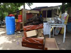 Residents of the community of Mexico in Gregory Park, St Catherine, pack their furniture to move from the area following a second firebombing this week.