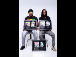 Suga Roy (left) and Conrad Crystal of The Fireball Crew showing off their awards for making it to number one positions in various iTunes reggae charts. 