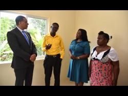 Prime Minister Andrew Holness (left) and Member of Parliament for North East St Catherine, Kerensia Morrison (second right) listen keenly to Delano Tucker while his mother Nattris Tucker looks on inside their new home.