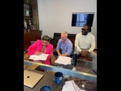 Dancehall artiste Ishawna (left), signs on the dotted line as Payday Record's Patrick Moxey and Producer Skatta Burrell look on. 