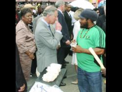 Prince Charles samples a piece of sugarcane given to him by Falmouth-based vendor Carlos Morgan (right) during his 2008 visit to Jamaica.