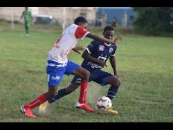 Holy Trinity’s Kimarley Graham (left) tries to shake the hounding Jaheem Frazer of Jamaica College (JC) during their ISSA/Digicel Manning Cup schoolboy football match at Bell/Chung Oval yesterday. JC won 4-2.