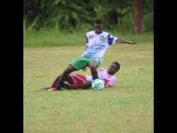 William Knibb’s Kernell Peart (standing) is tackled by Spot Valley High’s Khalid Stephenson during their ISSA/Digicel daCosta Cup match at William Knibb in their first clash of the season, recently. William Knibb won 3-0 as they also did yesterday in the second encounter at Spot Valley.