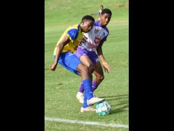 Taville Henry (left) of Ardenne shields the ball from Kingston College’s (KC) Samuel Shakes during their Manning Cup match at Stadium East on Friday. KC drubbed Ardenne 9-0.