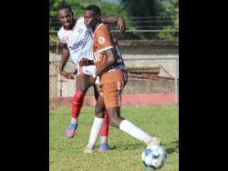 Glenmuir High’s captain Zakari Messam (left) makes a clearance before the onrushing Javel Barnes of Central High, during their ISSA daCosta Cup encounter on Thursday at Effortville Community Centre. The match ended in a 1-1 draw.