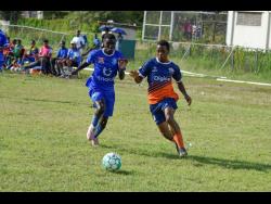 Kemar Beharie (right) of Dunoon Technical and Antonio Mitchell of Norman Manley High in a race for the ball  during the ISSA/Digicel Manning Cup match at the Excelsior High School playfield yesterday. Dunoon won 2-1. 