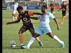 Odean Wilson (left) of Tivoli High school dribbles the ball away from Brian Burkett of St George’s College during their Walker Cup KO semi-final match at the Stadium East field yesterday. Tivoli won 1-0.
