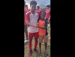 Campion College’s Kai Myles (left) poses with a young fan after scoring their goal in the 1-0 win over St George’s College in the Colts (under-16) final at Calabar yesterday.