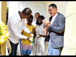 Prime Minister Andrew Holness (right) cheers as Norman Horne (left), chairman of ARC Properties Limited, assists 14-year-old Rohan Clarke and his mother, Sidoney Eldermire, (second right) to cut the ribbon to their new home on Thursday. They were joined by Charlotte Hayles, deputy chairman of ARC (in background). Eldemire received the house under the New Social Housing Programme during a small handover ceremony.
