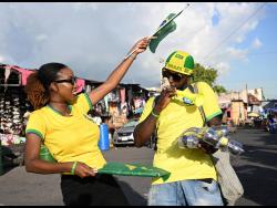 Cheers To The Cup co-host Shanel Lemmie (left) celebrates Brazil 2-0 win over Serbia with a flag vendor in downtown Kingston on November 24.