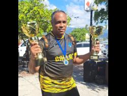 Andre Virtue, Ballaz Academy director,  holding the under-12 and under-10 championship trophies.