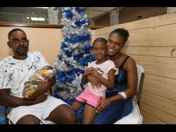 Christmas baby Teven Bryant relaxes in the arms of his father, Vencott Bryant, at the May Pen Hospital, Clarendon, on December 25. Sharing the moment are Tashoya Walford, the baby’s mother, and Vennecia Bryant, who is now a big sister.