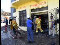Firemen moving their equipment from Lyn Max Bakery along Slipe Road in Kingston after extinguishing a blaze in the upper part of the establishment.