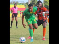 Humble Lion midfielder Andrew Vanzie (left) is clipped from behind by Tivoli Gardens midfielder Rodico Wellington during their Jamaica Premier League (JPL) encounter at Effortville Community Centre in Clarendon yesterday. Referee Nerisa Goldson watches the action closely as Humble Lion secured a 1-0 victory.