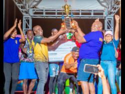  Dr Dwayne Vernon (third left), executive director of the Social Development Commission (SDC), presents the winning trophy to Vivian Brian Thomas, manager/captain of the Farm Town domino team, following their win in the SDC National 4-in-1 competition at the Discovery Bay Community Centre on Sunday.